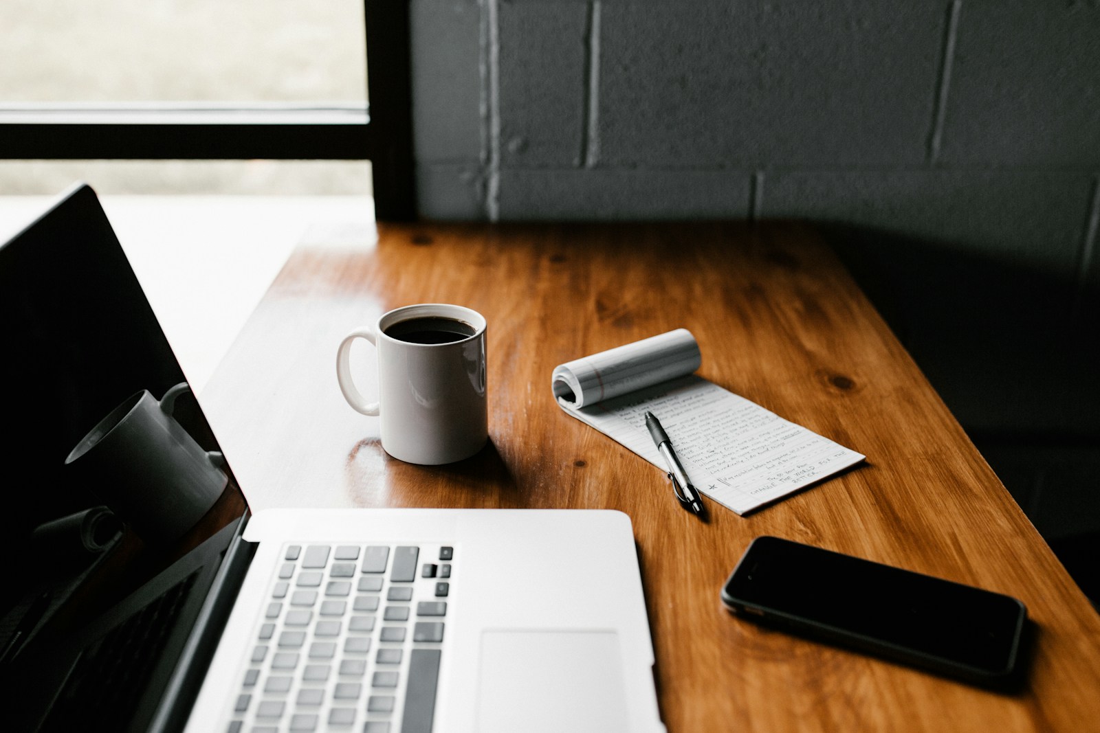 Minimalist desk with a laptop and coffee, representing three generations of writing